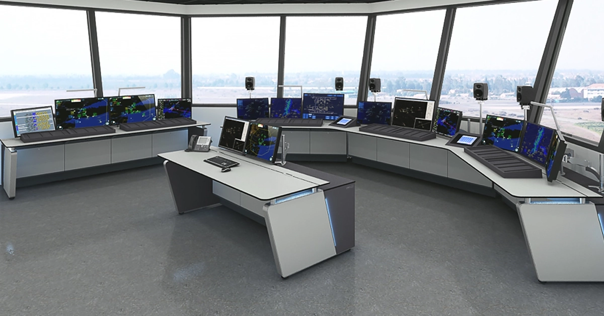 A modern air traffic control room with LundHalsey Air Traffic Control Room Consoles arranged in a U-shape, each equipped with multiple monitors displaying radar and flight data