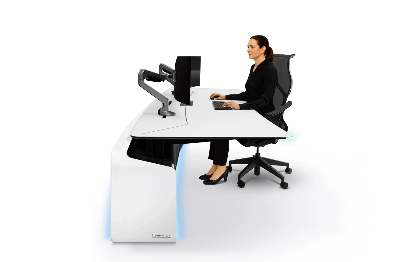 LundHalsey-Optima-Sit-Stand-Operator-Seated.webp Operator seated at lowered LundHalsey OPTIMA sit-stand control room console